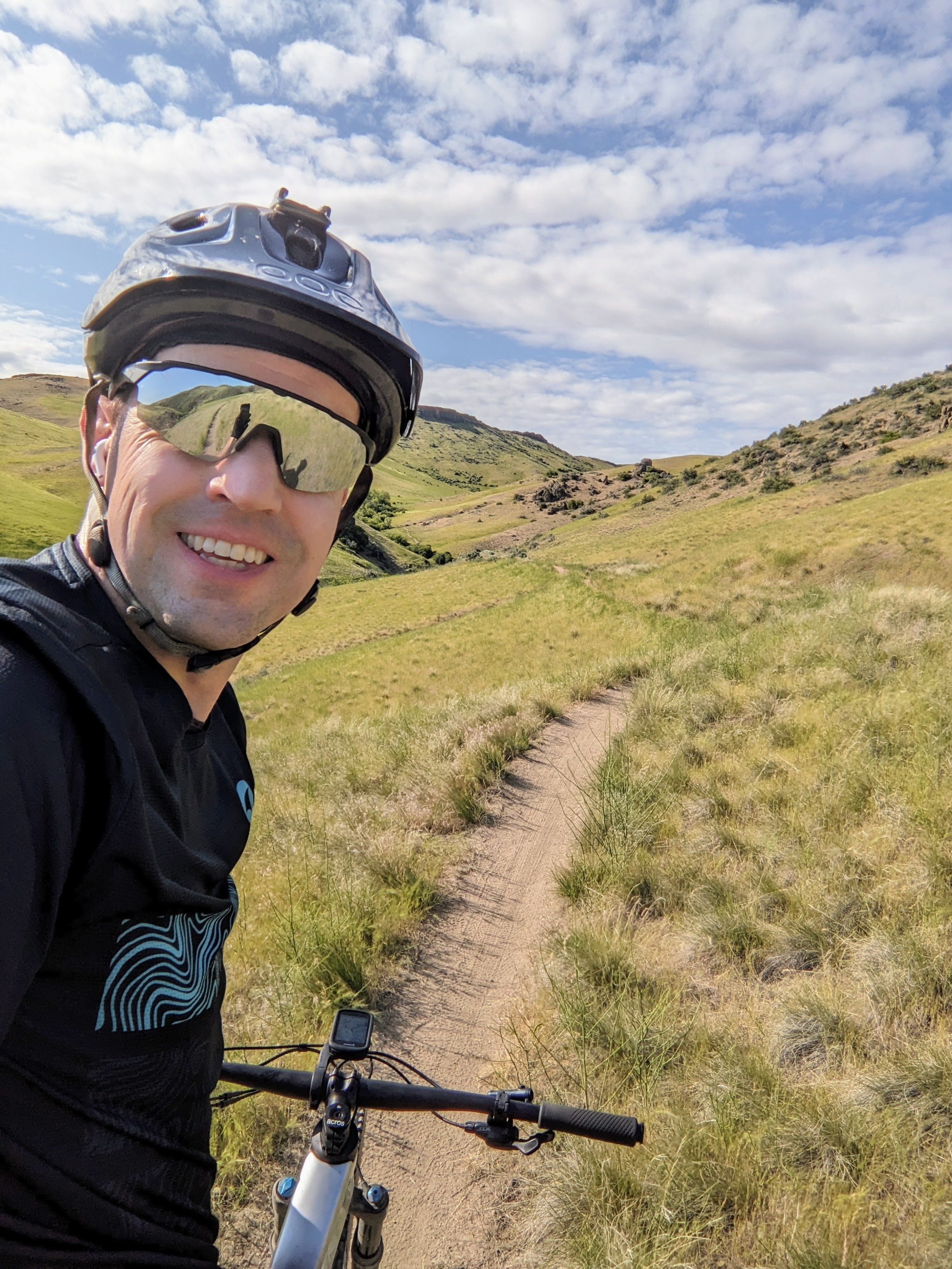Connor on his bike on a singletrack trail through green foothills